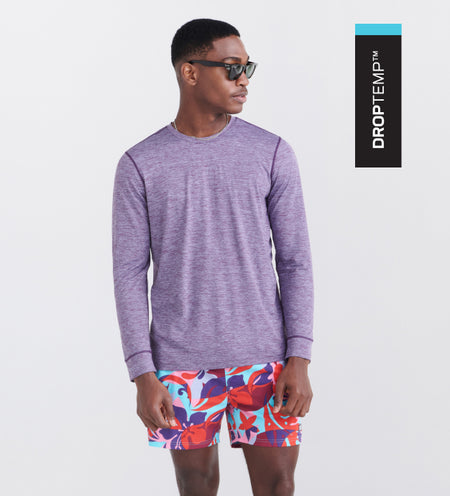 Man wearing a purple long sleeve tee and swim shorts in a floral pattern