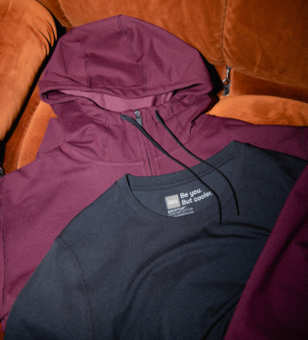 A maroon hoodie and black tee on an orange couch