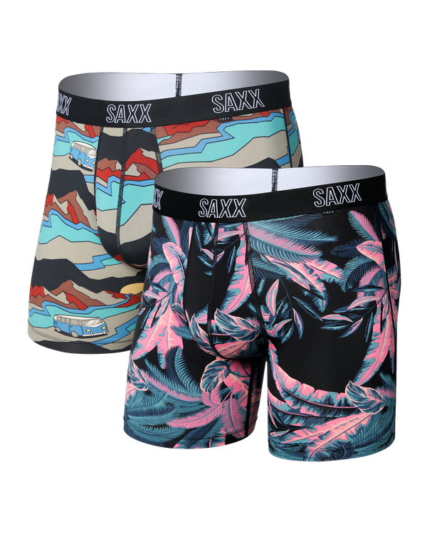 Two pairs of SAXX men's boxer briefs shown on a white background. The pair in the back has a multicolor abstract pattern, and the pair in the front has a black base with pink and teal tropical leaf print.