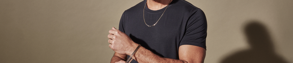 Man in black shirt and gold necklace with arms crossed
