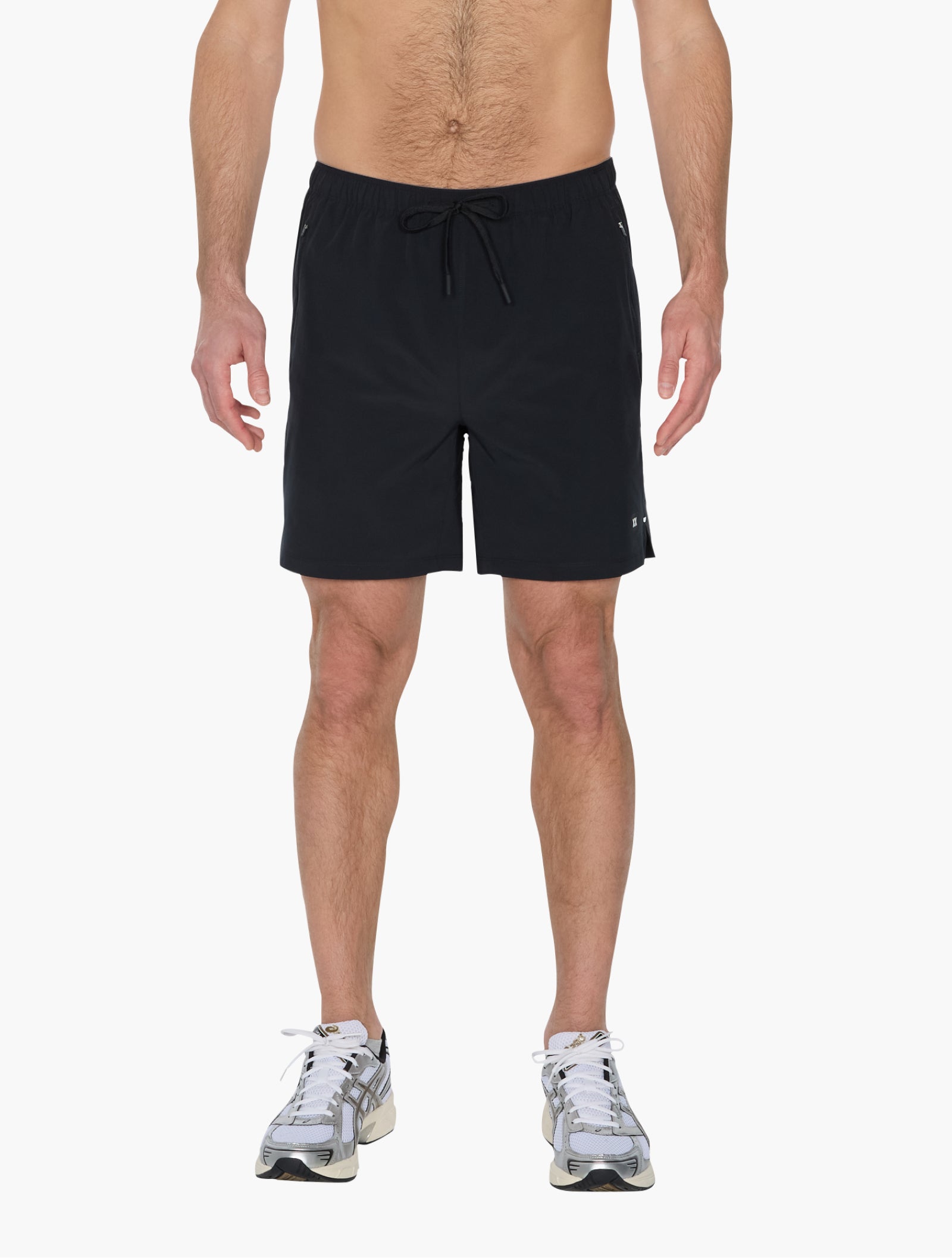 Man wearing black athletic shorts with drawstring standing forward showcasing lightweight sporty design with sneakers