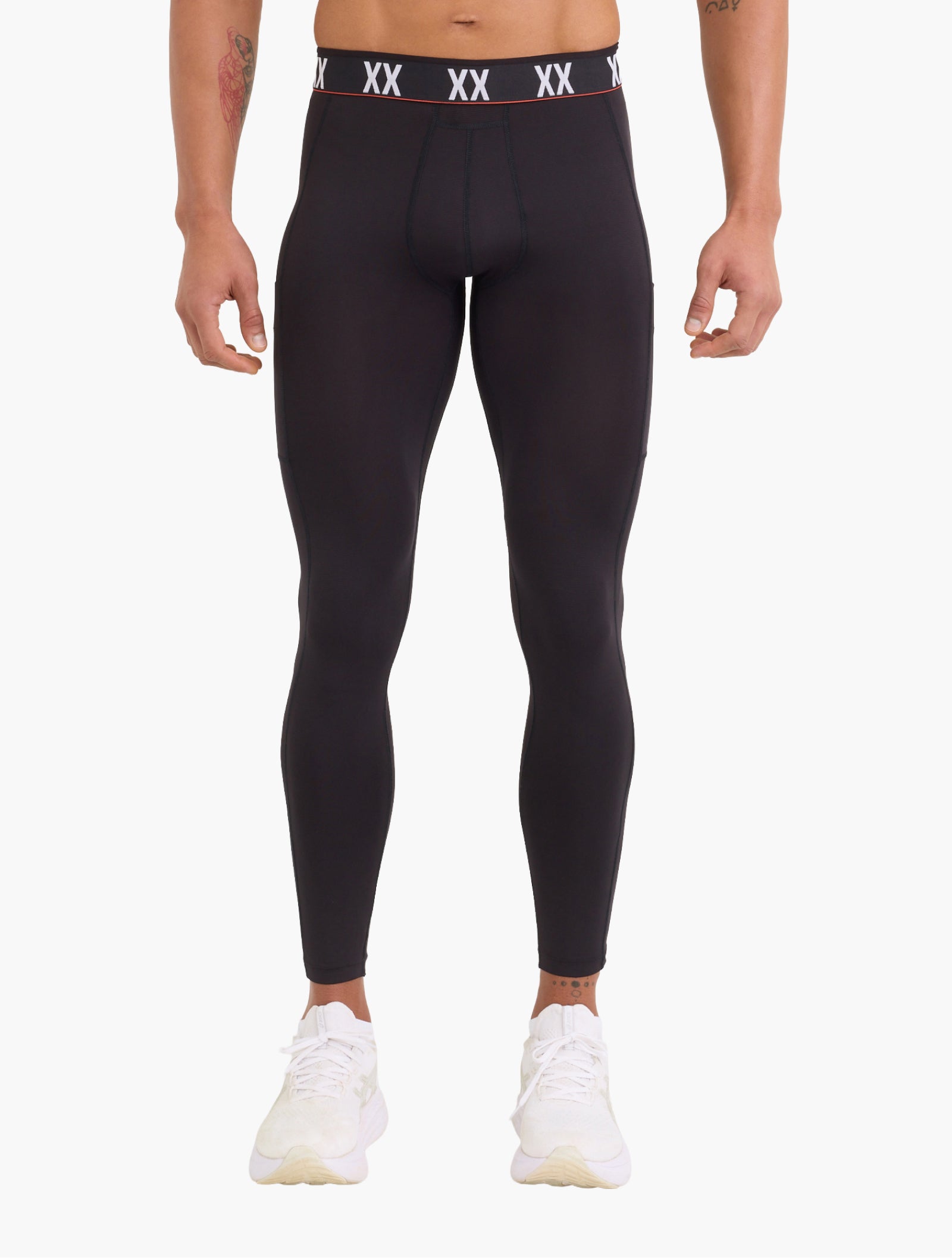 Front view of a model wearing black compression tights with full-length fitted silhouette and visible SAXX branded waistband.