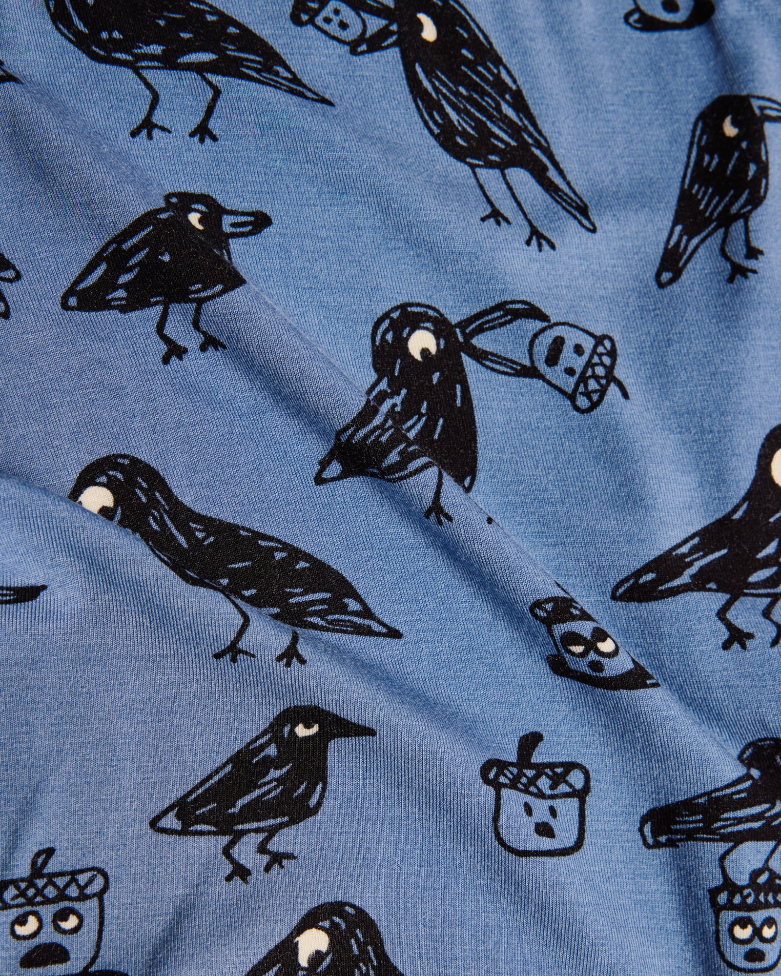 Blue fabric with black bird illustrations and acorns on a blue background