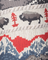 Close-up of a knitted printed fabric with red trees, gray bison, and blue mountains.