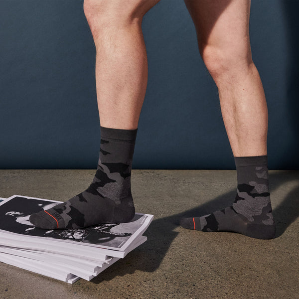Model posing in Whole Package Crew Sock in Supersize Camo- Black