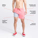 Man in pink swim shorts and red shoes lifting short leg to reveal liner