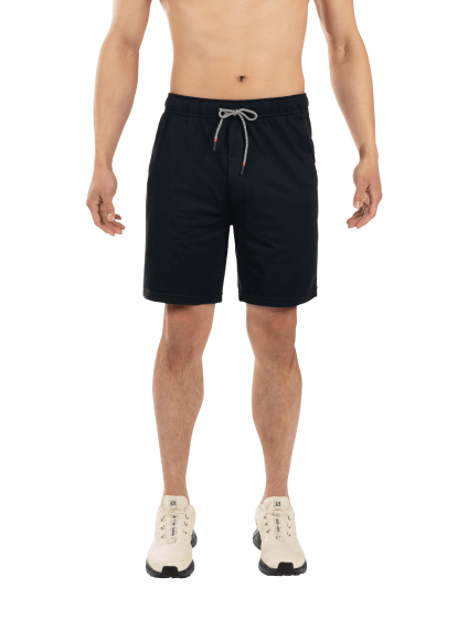 Shirtless man in black shorts and white shoes standing with arms at side